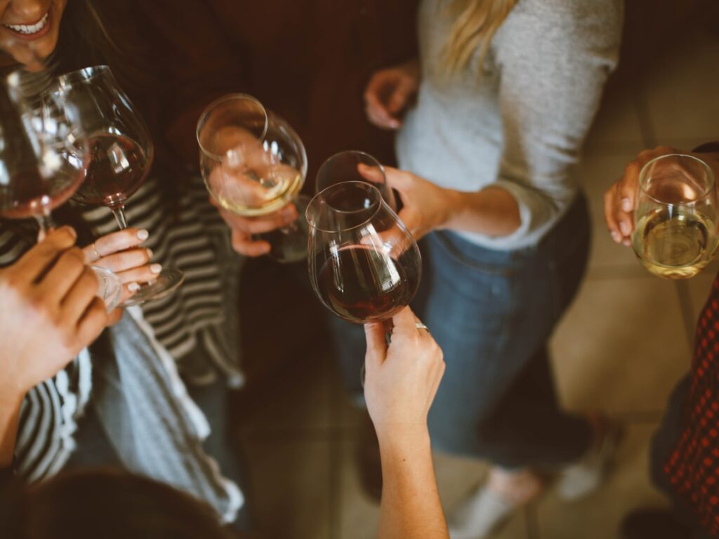 A top down view of a group of adults drinking alcohol and clinking wine glasses