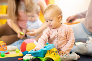 A baby plays with a plastic toy truck