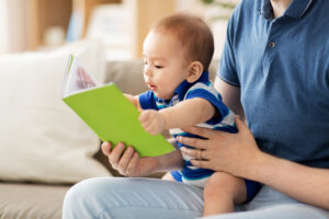baby boy and father with book at home